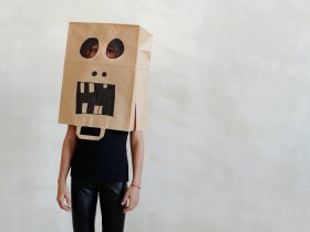 a kid wearing a funny face drawn on a paper bag